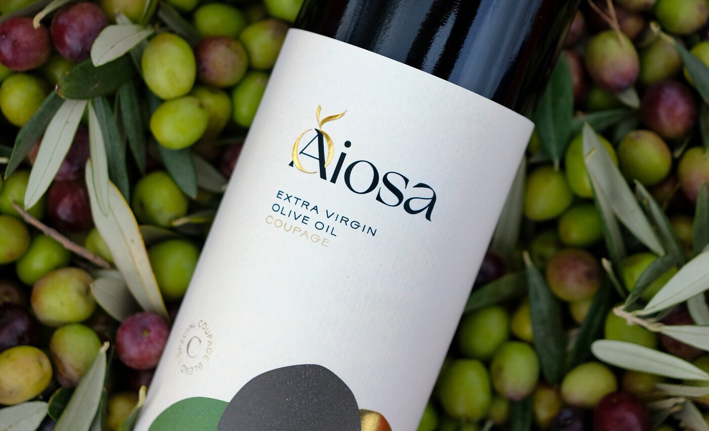 Botella de aceite de oliva Aiosa sobre aceitunas de diversas variedades